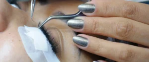 Lash artist applying an extension with tweezers during a salon service