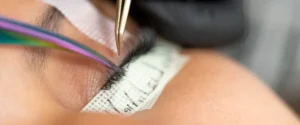 A lash artist working with tweezers and extensions in a salon setting