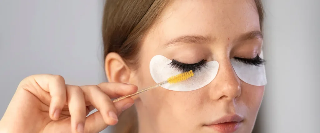 Brush applying strip lash adhesive along a lash band before application